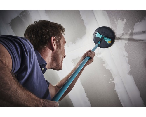 Man schuurt muur met schuurmachine voor renovatiewerkzaamheden