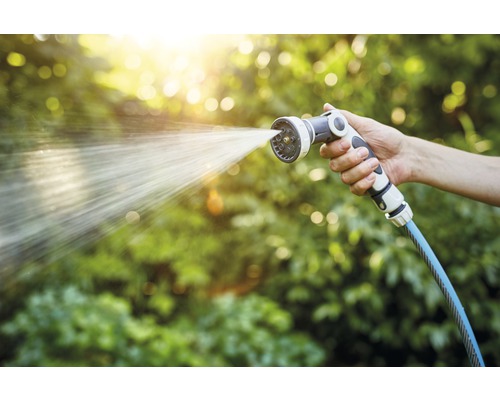 Een hand houdt een tuinspuit vast waar water uit komt