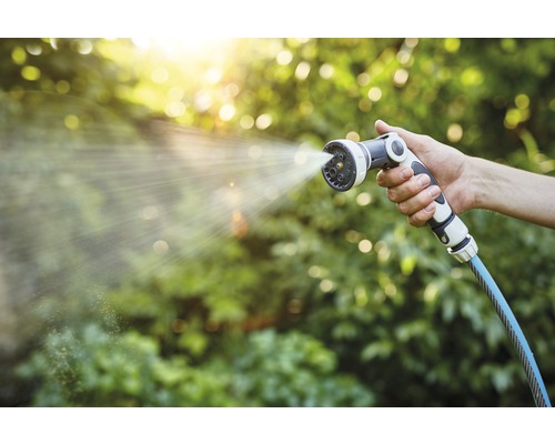 Een hand houdt een tuinspuit vast waar water uit komt.