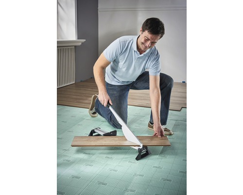 Een man snijdt een laminaatplank met een laminaatsnijder.