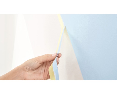 Een hand trekt een plakband van een muur af