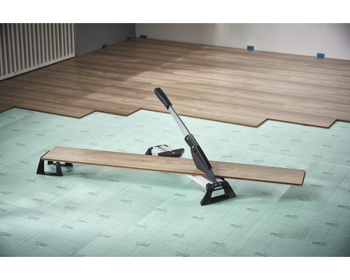 Laminaatsnijder in gebruik op geluidsreducerende ondervloer bij het leggen van laminaat