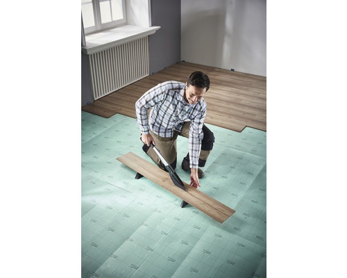 Man snijdt laminaat met laminaatsnijder op isolerende onderlaag in de kamer