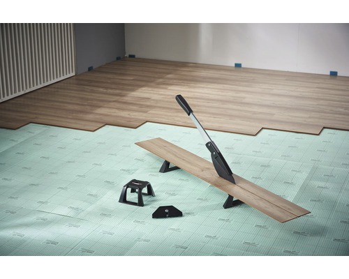 Laminaatsnijder in gebruik op isolerende onderlaag met laminaatvloer in de kamer