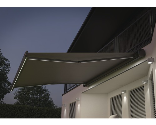 Uitgeklapt knikarmscherm met verlichting aan de muur van het huis