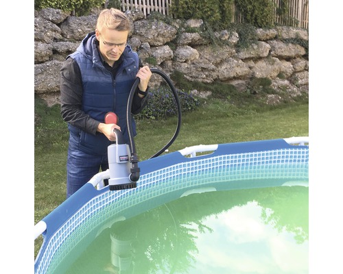 Man bedient een zwembadpomp bij een zwembad in de tuin.