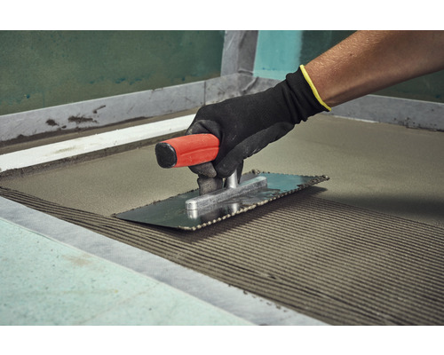 Tegelzetter met een vlakspaan voor het aanbrengen van tegellijm