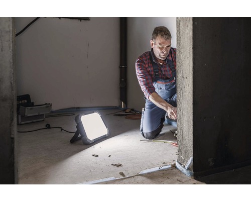 Ambachtsman aan het werk met een led bouwlamp in een ruwbouw