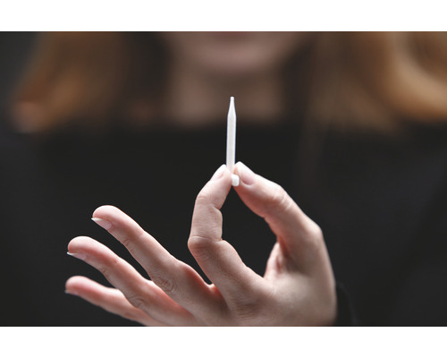 Een hand houdt een injector vast.