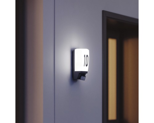 Verlicht huisnummerbord met nummer 10 aan de muur