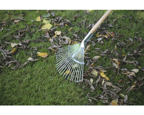 Metalen bladbezem met houten steel op gazon met bladeren