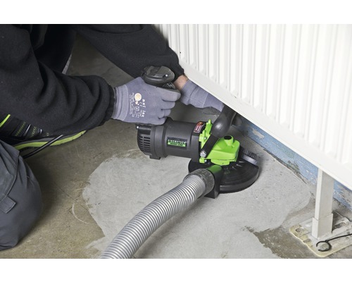 Man gebruikt een betonrenovatiefrees bij een radiator op de vloer