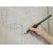 Een persoon tekent met een Pica Classic 541 stift een pijpschets op een betonnen muur.