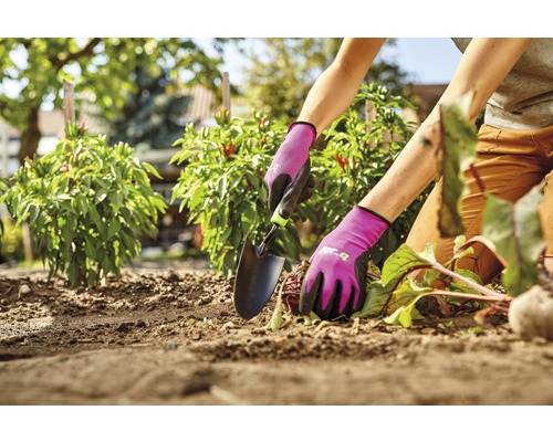 Persoon werkt in de tuin met een plantspatel en tuinhandschoenen.