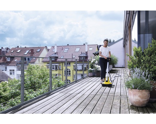 Vrouw reinigt houten terras met terrasreiniger