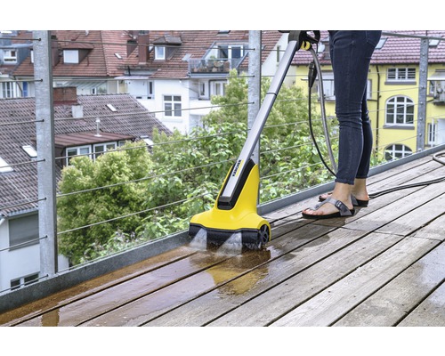 Vrouw reinigt houten terras met Kärcher terrasreiniger