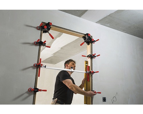 Een man monteert een deur in een ruwbouw met een deurkozijnmal.