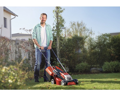 Een man gebruikt een grasmaaier in de tuin.