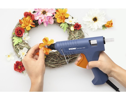 Decoratieve bloemenkrans wordt versierd met een lijmpistool