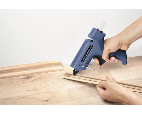 Iemand lijmt sierlijsten met een lijmpistool.