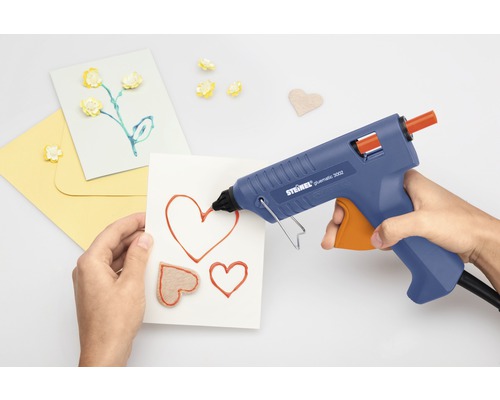 Persoon gebruikt lijmpistool voor het maken van kaarten