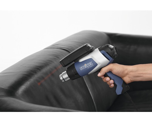 Persoon houdt Steinel HL 2020 E heteluchtpistool boven een leren bank