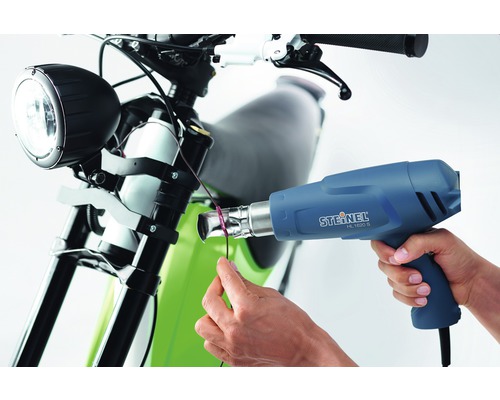 Een persoon gebruikt een Steinel HL 1620 S heteluchtpistool op een motorfiets.