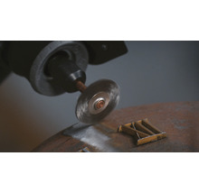 Draadborstelopzetstuk op een boormachine tijdens het ontroesten van een metalen stuk