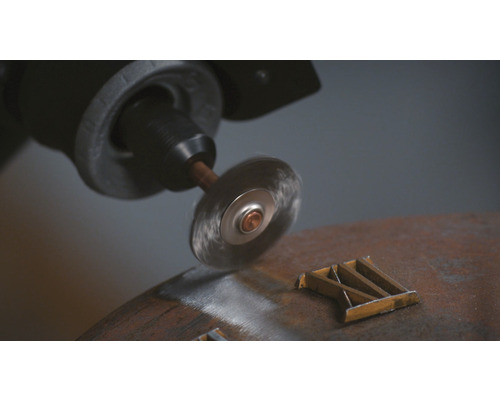 Draadborstelopzetstuk op een boormachine tijdens het ontroesten van een metalen stuk