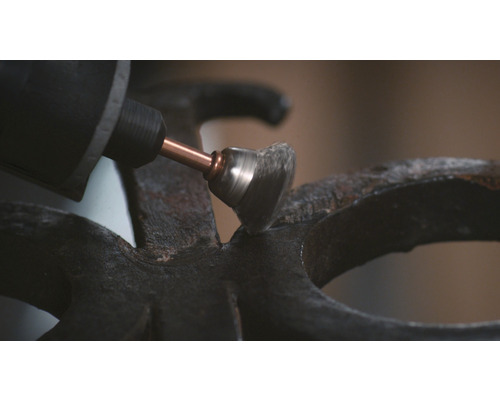 Een slijpmachine met draadborstelopzetstuk slijpt een metalen oppervlak.