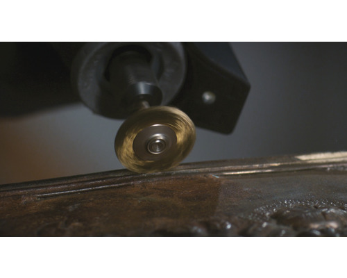 Roterende draadborstel bevestigd aan een multifunctioneel gereedschap dat aan metaal werkt