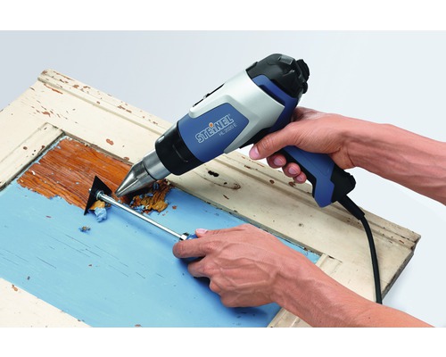 Verf wordt verwijderd van een houten frame met een heteluchtpistool en een plamuurmes