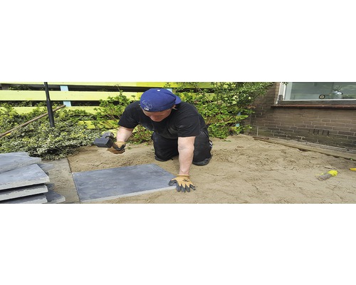 Man legt tuintegels met een rubberen hamer