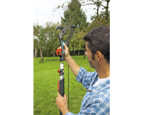 Een man monteert een Gardena takkenschaar aan een telescopische steel in de tuin.