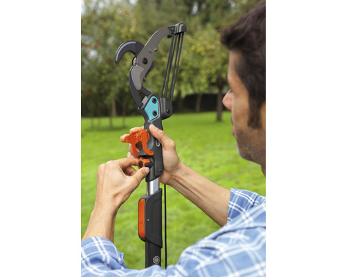 Een man bedient een telescopische takkenschaar in de tuin.