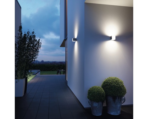 Buitenkant van een huis met twee moderne wandlampen die de gevel verlichten