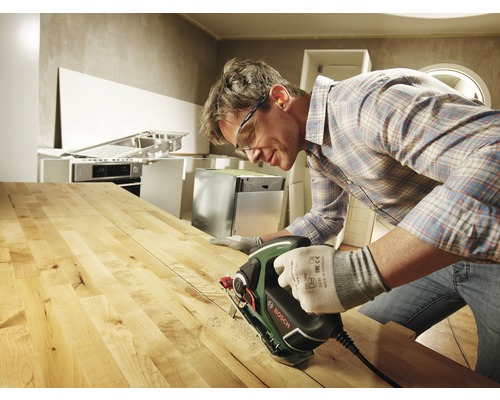 Man zaagt houten plaat met decoupeerzaag. Bosch logo.