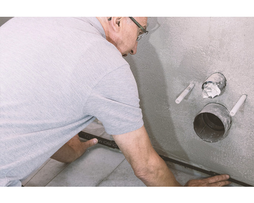 Man installeert tegelprofiel in badkamer.