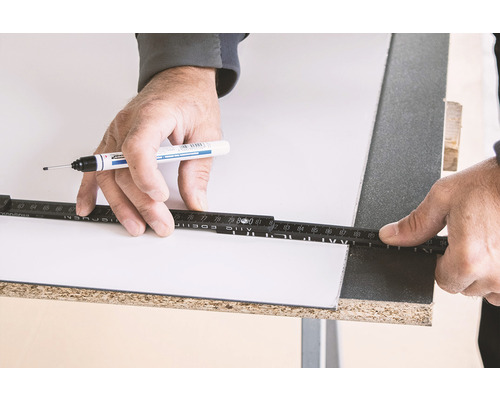 Een persoon markeert een plaat met een stift en een duimstok.