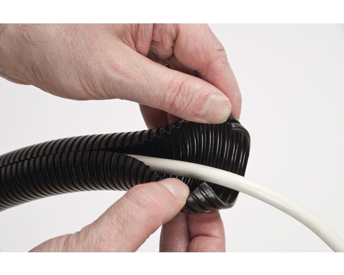 Een persoon plaatst een witte kabel in een zwarte geribbelde buis