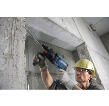 Man boort met een Bosch boorhamer in een betonnen muur