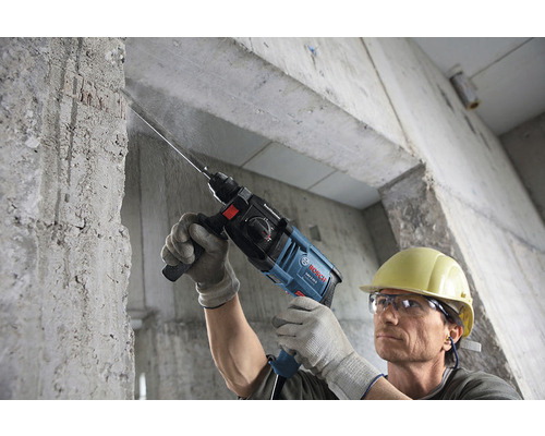Man boort met een Bosch boorhamer in een betonnen muur