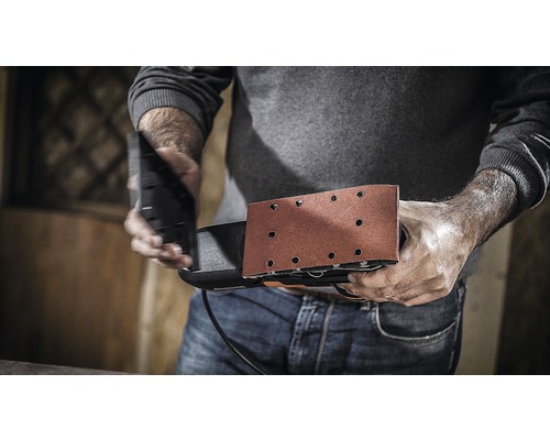 Een man houdt een vlakschuurmachine klaar voor gebruik.