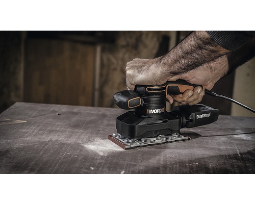 Een persoon gebruikt een WORX excentrische schuurmachine op een houten oppervlak.