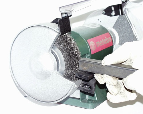 Metabo tafelslijpmachine met draadborstel bij het ontroesten van een metalen stuk