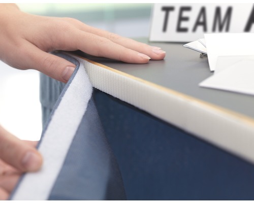 Persoon bevestigt een accessoire met klittenband aan een tafel