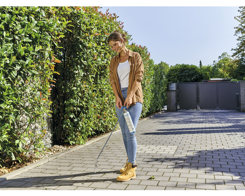 Een vrouw gebruikt een gasbrander voor onkruidbestrijding in de tuin.