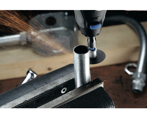 Een pijpklem houdt een buis vast terwijl een multifunctioneel gereedschap het bewerkt en er vonken vanaf komen.