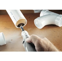Een persoon snijdt een kunststof buis met een multifunctioneel gereedschap.