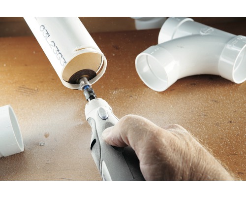 Een persoon snijdt een kunststof buis met een multifunctioneel gereedschap.